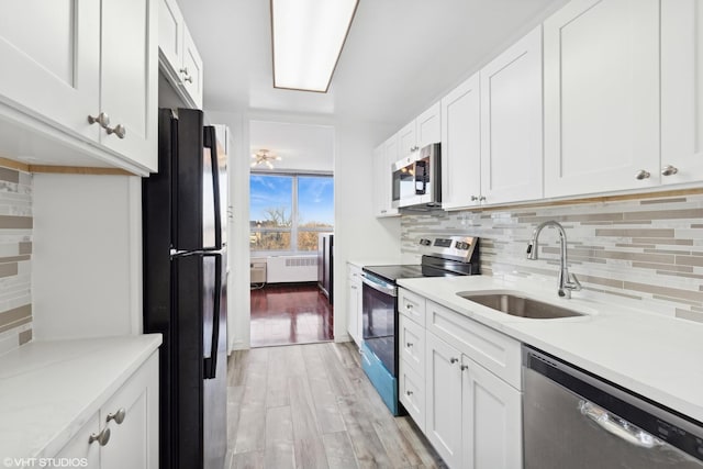 kitchen with radiator heating unit, tasteful backsplash, white cabinetry, sink, and stainless steel appliances