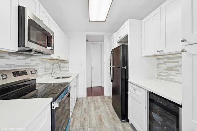 kitchen featuring stainless steel appliances, sink, white cabinets, and wine cooler