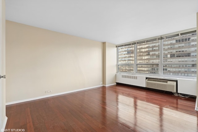 spare room featuring a wall mounted air conditioner and hardwood / wood-style floors