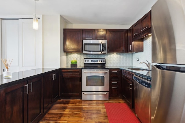 kitchen with appliances with stainless steel finishes, dark hardwood / wood-style floors, pendant lighting, sink, and backsplash