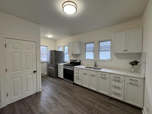 kitchen with sink, dark wood-type flooring, appliances with stainless steel finishes, white cabinetry, and backsplash