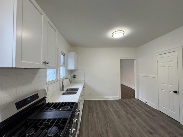 kitchen featuring sink, dark hardwood / wood-style floors, stainless steel range with gas stovetop, white cabinets, and decorative backsplash