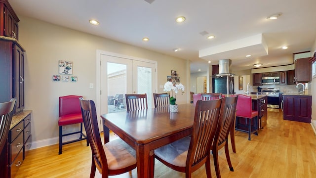 dining space with sink, french doors, and light wood-type flooring