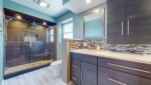 bathroom featuring tasteful backsplash, vanity, a shower with door, and toilet