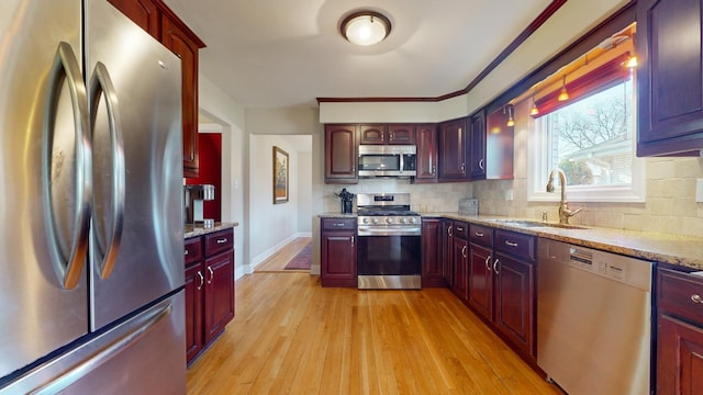 kitchen featuring sink, light hardwood / wood-style flooring, appliances with stainless steel finishes, backsplash, and light stone counters