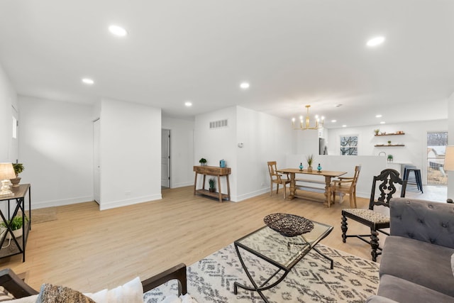 living room with an inviting chandelier and light hardwood / wood-style flooring