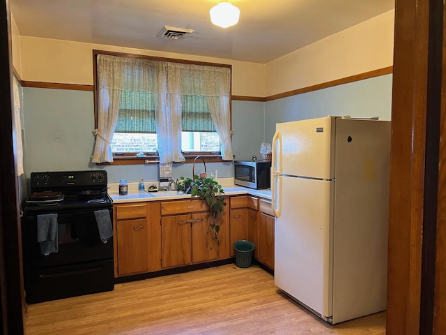 kitchen with sink, black electric range, white fridge, and light hardwood / wood-style flooring