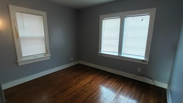 unfurnished room with dark wood-type flooring