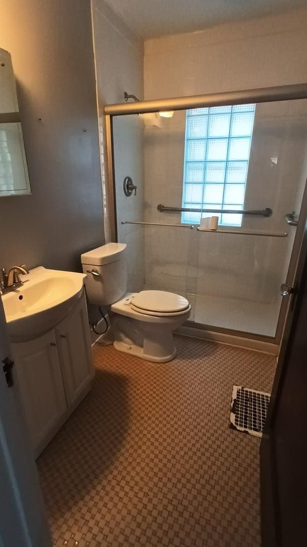 bathroom featuring tile patterned floors, toilet, a shower with shower door, and vanity