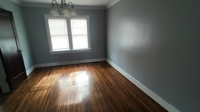 unfurnished room featuring a notable chandelier, crown molding, and dark wood-type flooring