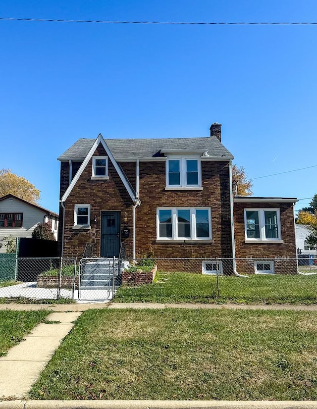 view of front of property with a fenced front yard, a front yard, brick siding, and a chimney