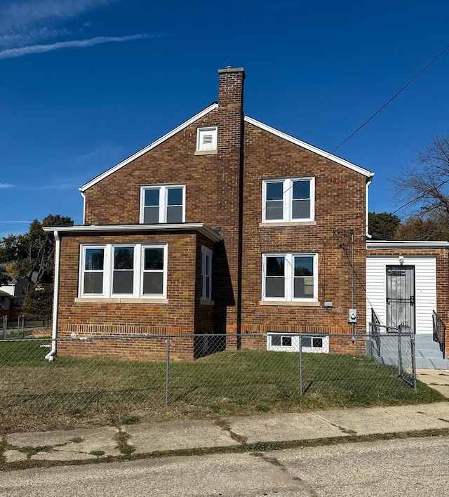 view of side of property with a yard, brick siding, a fenced front yard, and a chimney