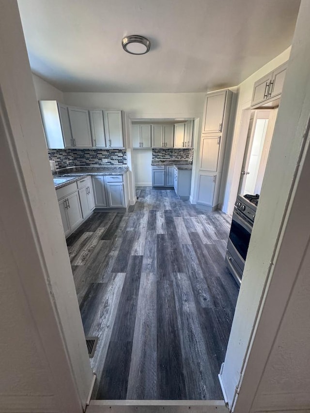 kitchen featuring dark wood-style floors, white cabinets, decorative backsplash, and gas stove