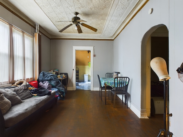 living room with a raised ceiling, crown molding, dark hardwood / wood-style floors, and ceiling fan