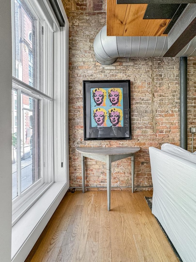 interior space featuring brick wall, plenty of natural light, and light hardwood / wood-style flooring