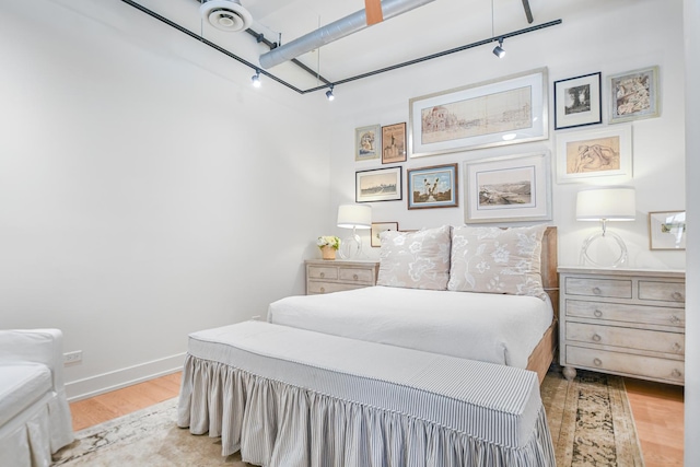 bedroom featuring rail lighting and light hardwood / wood-style flooring