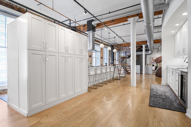 basement featuring wine cooler, sink, and light wood-type flooring