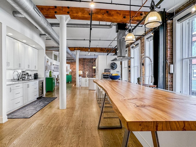 kitchen featuring white cabinetry, decorative light fixtures, light hardwood / wood-style floors, and a towering ceiling