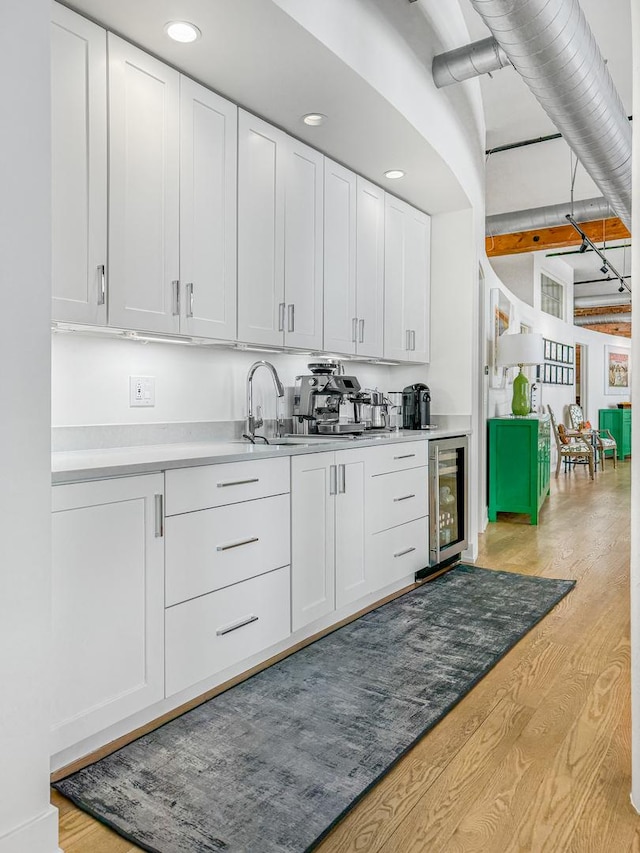 kitchen featuring white cabinetry, beverage cooler, and light hardwood / wood-style floors