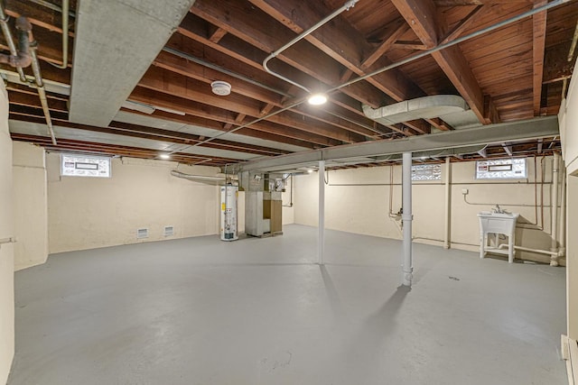 basement with water heater, sink, a healthy amount of sunlight, and heating unit