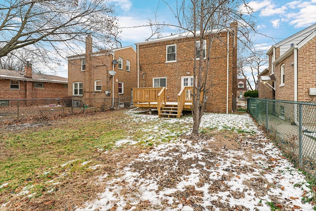 snow covered back of property with a deck