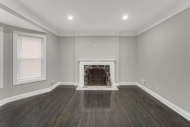 unfurnished living room featuring dark hardwood / wood-style floors, a premium fireplace, and crown molding