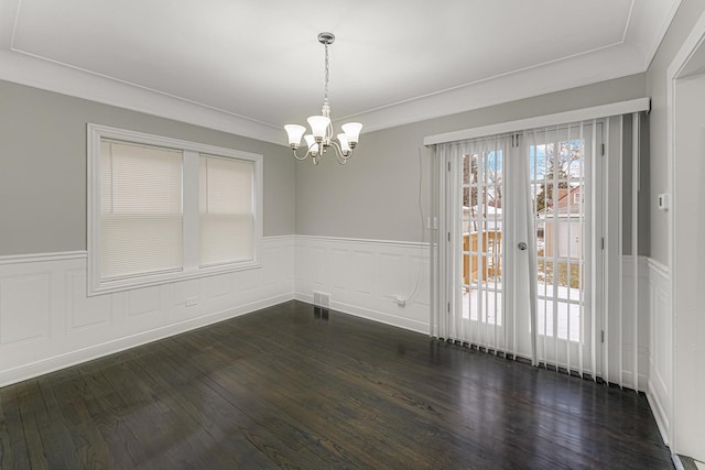 unfurnished dining area featuring crown molding, dark wood-type flooring, and a notable chandelier