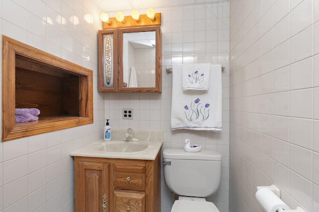 bathroom with vanity, toilet, and tile walls