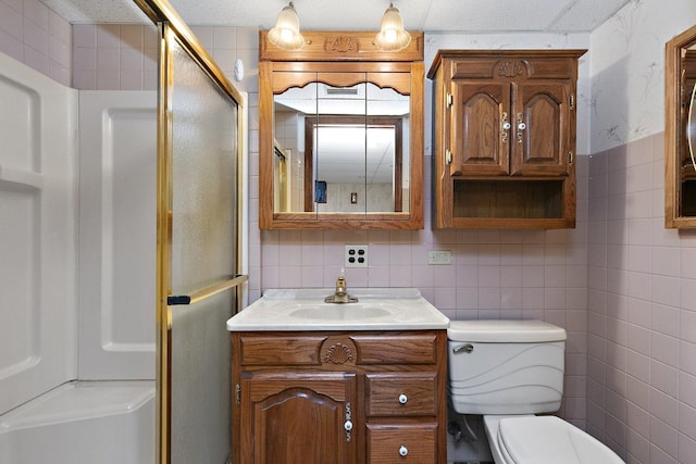 bathroom featuring vanity, toilet, tile walls, and a shower with shower door