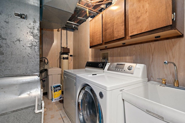 clothes washing area featuring sink, washer and clothes dryer, cabinets, and wood walls