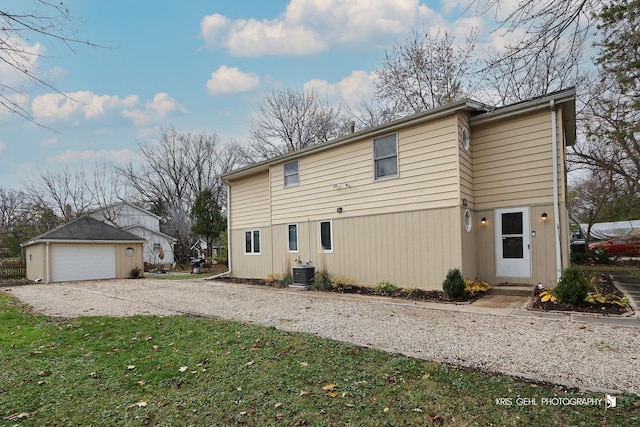 rear view of property featuring a garage, an outbuilding, and cooling unit