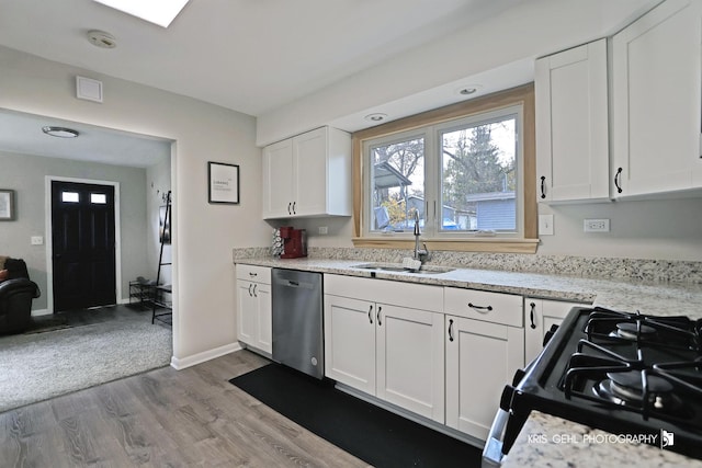 kitchen with white cabinetry, sink, stainless steel dishwasher, light hardwood / wood-style floors, and gas stove