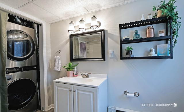 bathroom with stacked washer / dryer, vanity, and a paneled ceiling