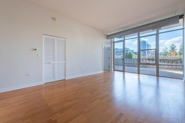 unfurnished room featuring expansive windows and hardwood / wood-style floors