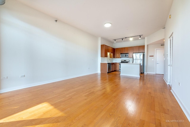 unfurnished living room featuring rail lighting and light wood-type flooring