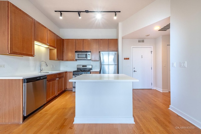 kitchen with a kitchen island, appliances with stainless steel finishes, sink, and light hardwood / wood-style floors