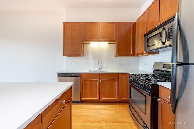 kitchen with stainless steel appliances, sink, and light hardwood / wood-style flooring