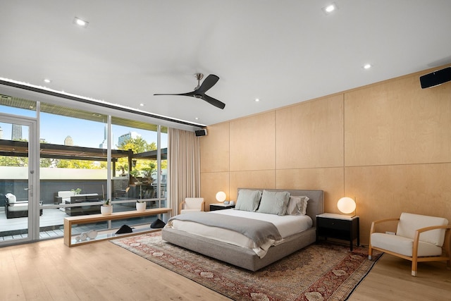 bedroom featuring access to exterior, a wall of windows, light hardwood / wood-style floors, and ceiling fan