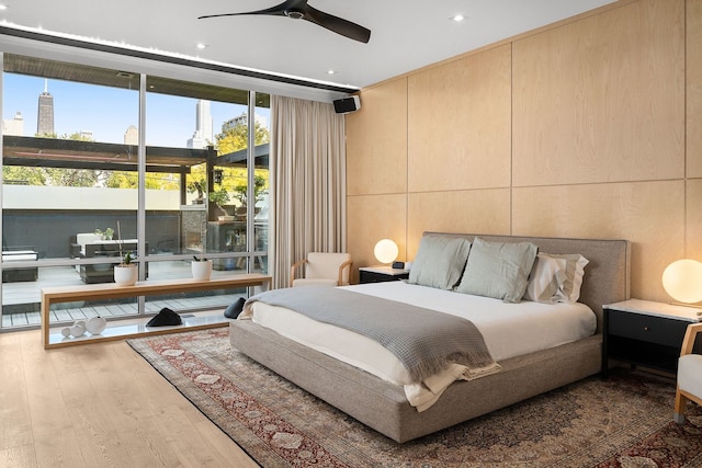 bedroom featuring ceiling fan, floor to ceiling windows, and light hardwood / wood-style flooring