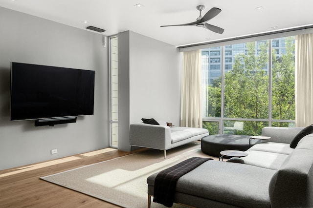 living room with hardwood / wood-style floors, a wall of windows, and ceiling fan