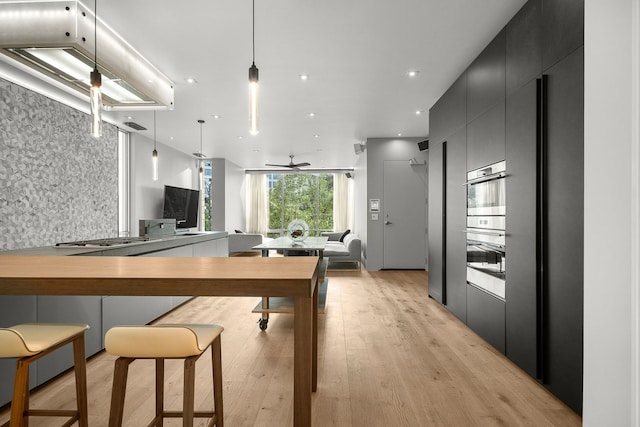 kitchen with light hardwood / wood-style flooring, kitchen peninsula, ceiling fan, and decorative light fixtures