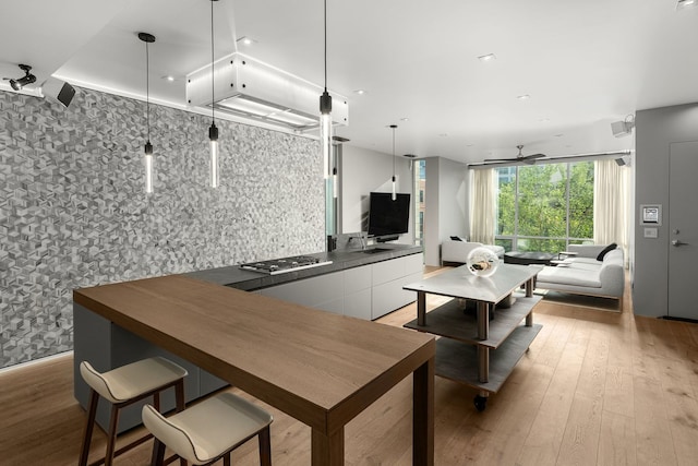 kitchen with decorative light fixtures, tasteful backsplash, white cabinetry, stainless steel gas cooktop, and light hardwood / wood-style floors