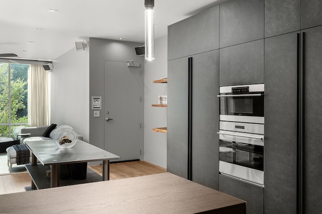 kitchen with pendant lighting, double oven, gray cabinets, and light hardwood / wood-style floors