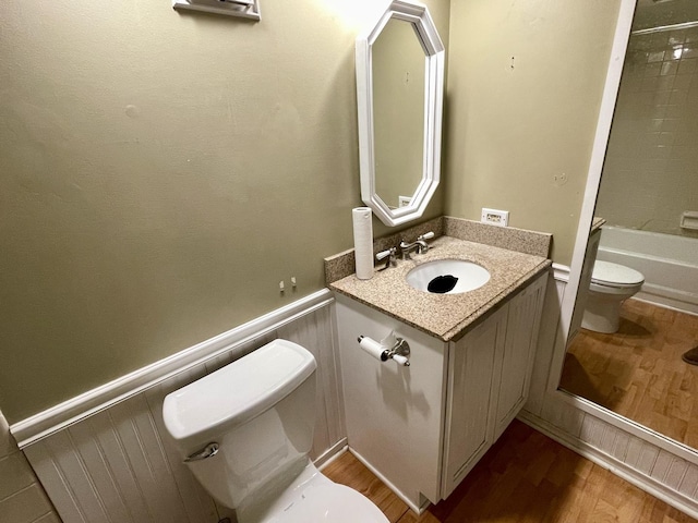 full bathroom with vanity, tiled shower / bath, wood-type flooring, and toilet