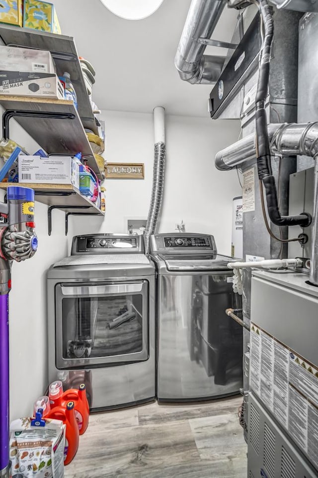 laundry area featuring washing machine and clothes dryer and light hardwood / wood-style flooring