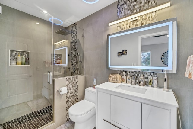 bathroom with walk in shower, vanity, toilet, and tile walls