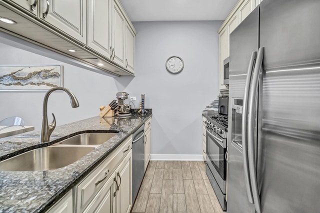 kitchen with stainless steel appliances, sink, and dark stone countertops