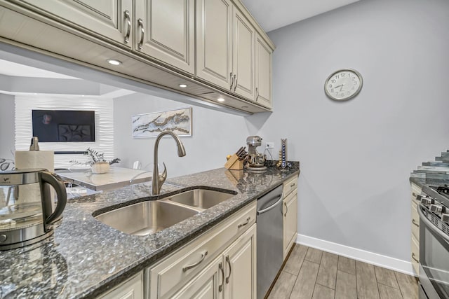 kitchen featuring appliances with stainless steel finishes, sink, dark stone countertops, and cream cabinets