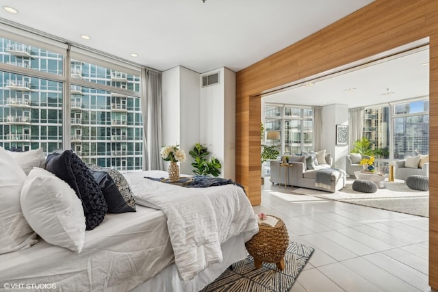 bedroom featuring expansive windows, light tile patterned flooring, and wood walls