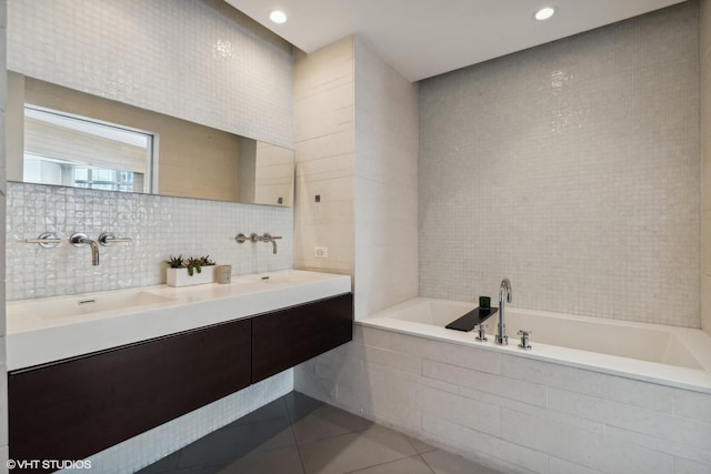 bathroom featuring tile patterned floors, tile walls, vanity, tiled bath, and backsplash